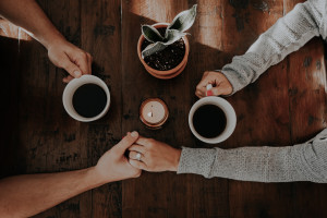 Photograph of two people chatting and drinking coffee, taken from above the table.