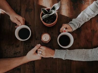 Photograph of two people chatting and drinking coffee, taken from above the table.