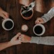 Photograph of two people chatting and drinking coffee, taken from above the table.